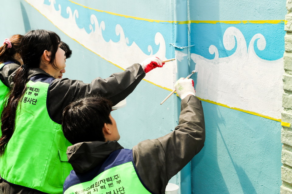 한수원 고리본부 임직원 봉사대와 대학생 봉사자들이 기장군 일광읍 학리마을에서 벽화를 그리고 있다.